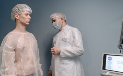 A doctor examines a patient in a clinic wearing medical gowns for a mole pathology evaluation.