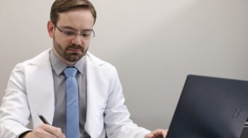 Dr. Tiago Guirro anotando o plano de tratamento de HPV no consultório
