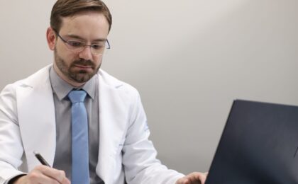 Dr. Tiago Guirro anotando o plano de tratamento de HPV no consultório